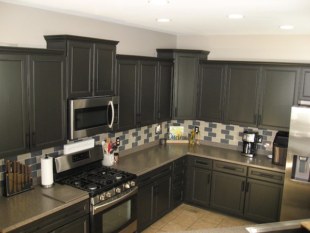 kitchen with light tile patterned floors, dark cabinets, appliances with stainless steel finishes, and decorative backsplash