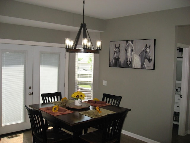 dining space with dark tile patterned flooring, a chandelier, french doors, and visible vents