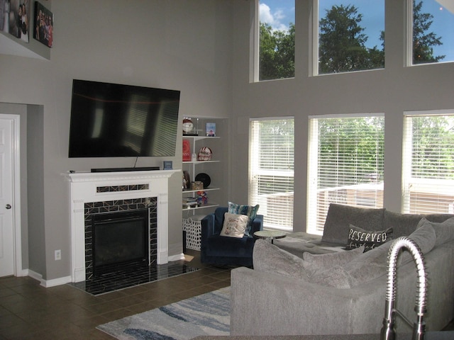 tiled living area featuring baseboards, a tile fireplace, and a high ceiling