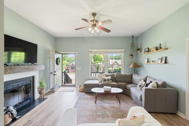 living room featuring baseboards, a ceiling fan, wood finished floors, and a fireplace
