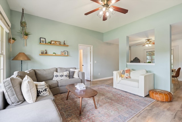 living room featuring baseboards, ceiling fan, and wood finished floors