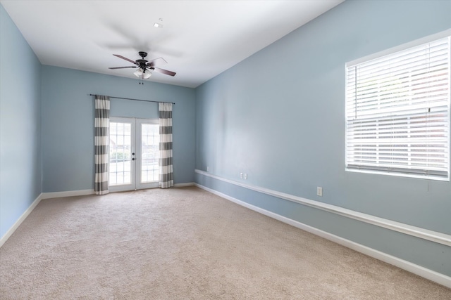 carpeted spare room with a ceiling fan, baseboards, and french doors