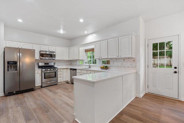 1069 Fitzpatrick Rd, Nashville, TN 37214 - kitchen featuring appliances with stainless steel finishes, a peninsula, light wood-style flooring, backsplash, and recessed lighting