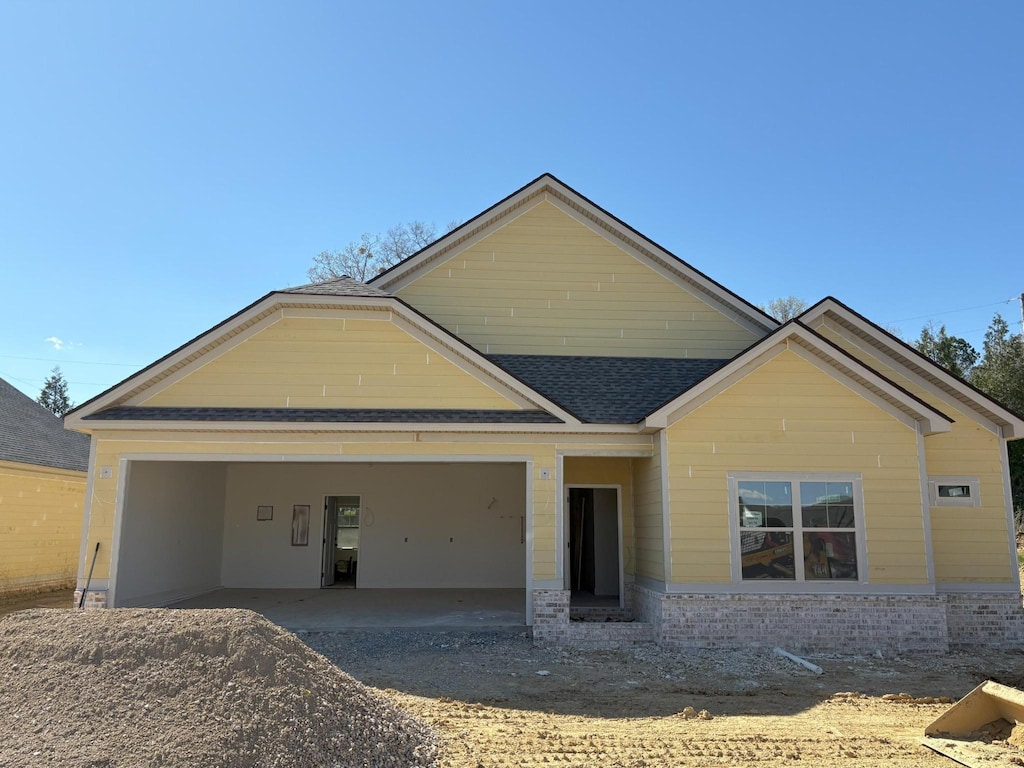 view of front of home with a shingled roof, dirt driveway, an attached garage, and brick siding
