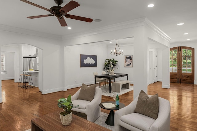 living area featuring arched walkways, wood finished floors, baseboards, ceiling fan with notable chandelier, and recessed lighting