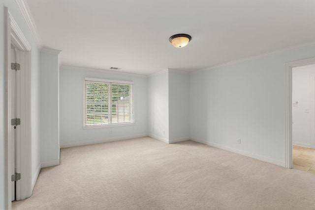 spare room featuring crown molding, baseboards, visible vents, and light carpet