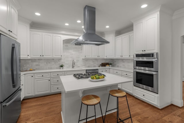 kitchen with white cabinetry, appliances with stainless steel finishes, backsplash, and island range hood