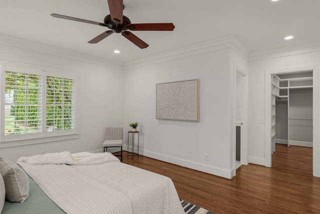 bedroom with crown molding, baseboards, wood finished floors, and a spacious closet