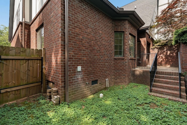 view of property exterior featuring brick siding and fence