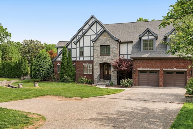 tudor home with concrete driveway, a front yard, a shingled roof, and stone siding