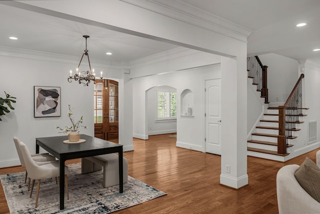 dining area with baseboards, ornamental molding, arched walkways, and stairs