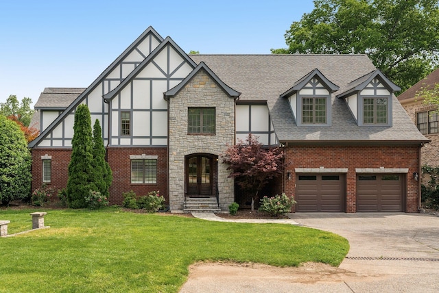 tudor house with a garage, a front lawn, stucco siding, a shingled roof, and concrete driveway