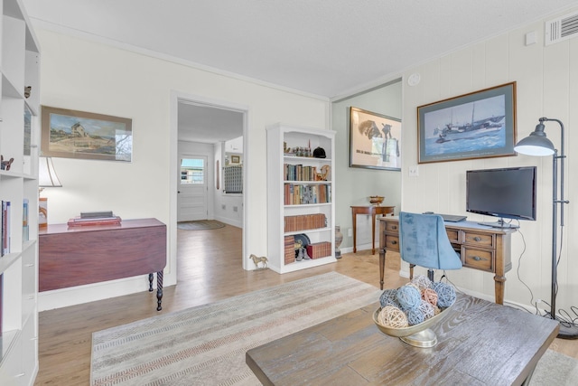 office space featuring crown molding, baseboards, visible vents, and wood finished floors
