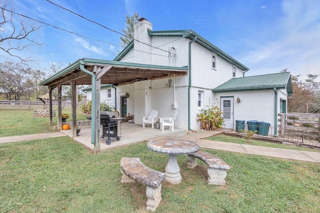 back of house featuring a patio area, fence, brick siding, a yard, and a chimney