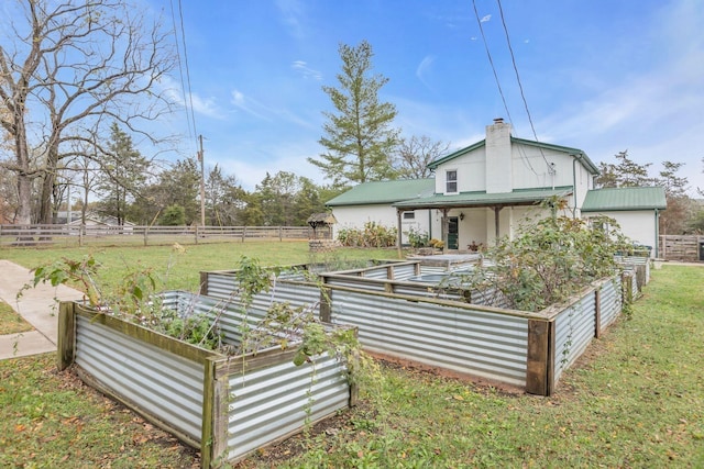 back of house with fence, a chimney, and a garden