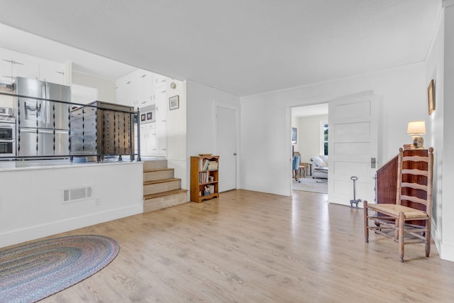 interior space with stairs, light wood finished floors, and visible vents