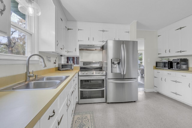 kitchen featuring under cabinet range hood, plenty of natural light, a sink, light countertops, and appliances with stainless steel finishes