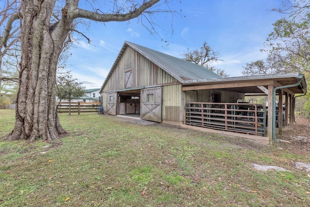 view of barn featuring an exterior structure, fence, and a lawn