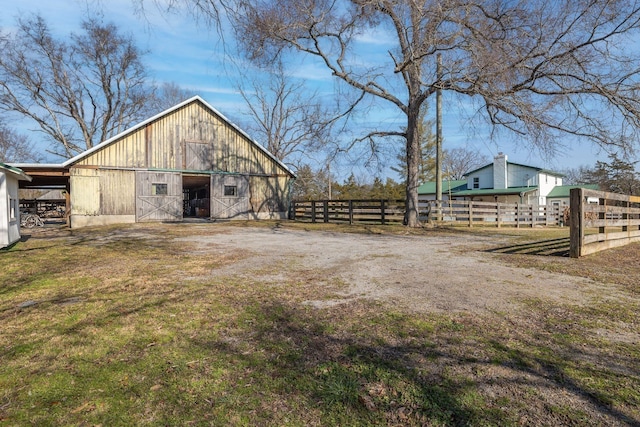 view of yard with an outbuilding, a detached garage, fence, and a barn