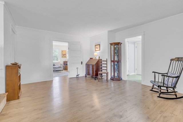 interior space featuring baseboards, light wood-style floors, and crown molding