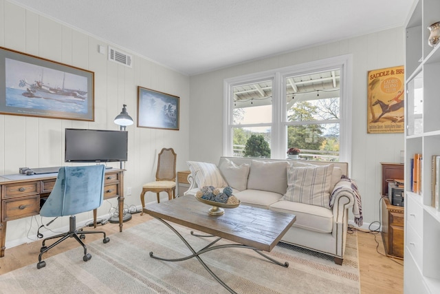 office with crown molding, a decorative wall, visible vents, and wood finished floors