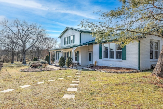 traditional home featuring covered porch, brick siding, and a front yard