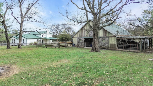 view of yard with an outdoor structure, fence, and a barn