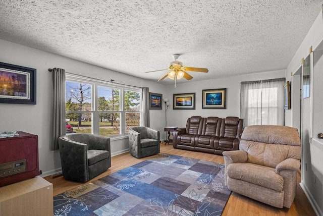 living room featuring ceiling fan, a textured ceiling, a wealth of natural light, and wood finished floors