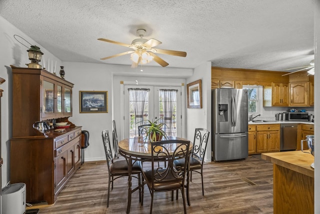 dining area with french doors, a textured ceiling, a healthy amount of sunlight, ceiling fan, and dark wood-style floors