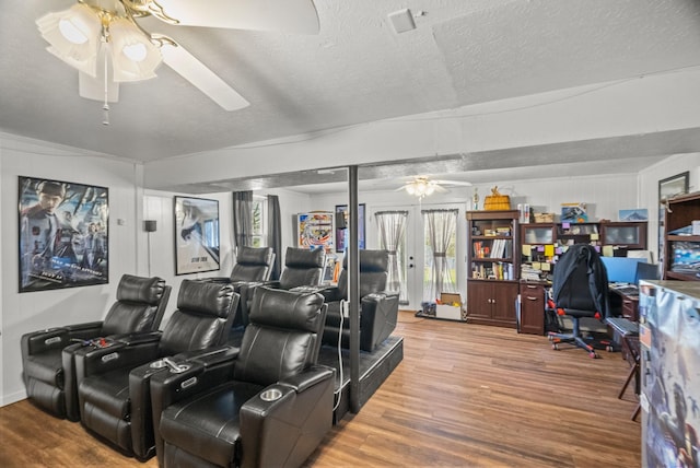 home theater room featuring a textured ceiling, a ceiling fan, and wood finished floors