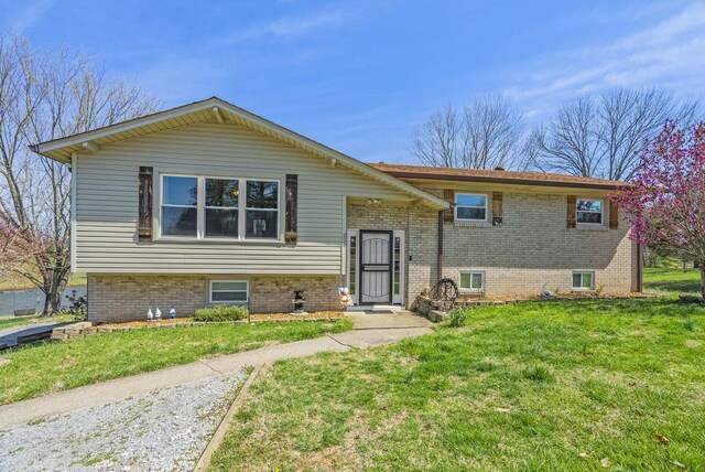 raised ranch with brick siding and a front yard