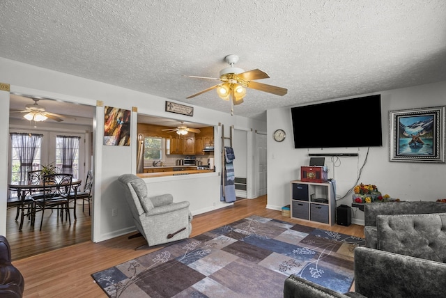 living area featuring a textured ceiling, a ceiling fan, and wood finished floors