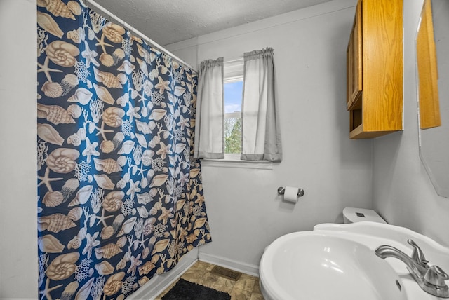 full bathroom with a textured ceiling, baseboards, visible vents, a sink, and curtained shower