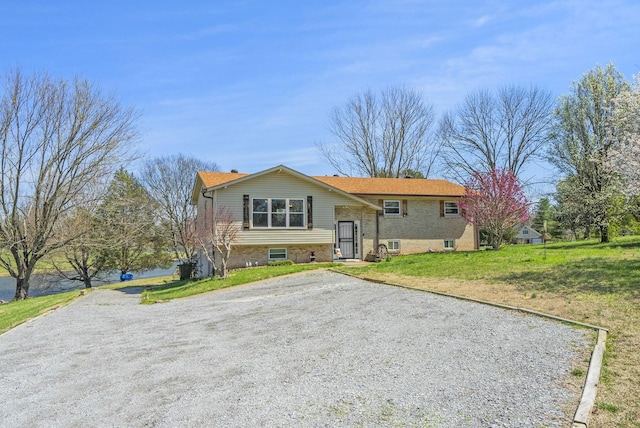 raised ranch featuring a front lawn and brick siding