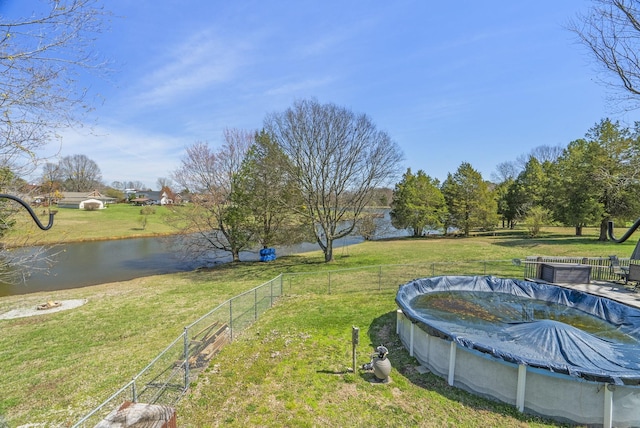 view of yard with a water view, fence, and a covered pool