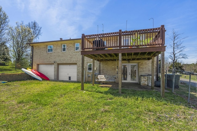 back of property with a yard, brick siding, french doors, fence, and a wooden deck