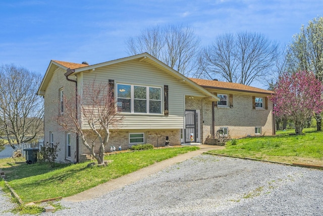 split foyer home with a front lawn and brick siding