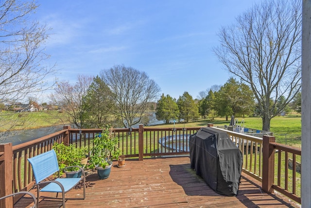 wooden deck featuring a water view, a yard, and grilling area