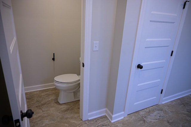 bathroom featuring toilet and baseboards