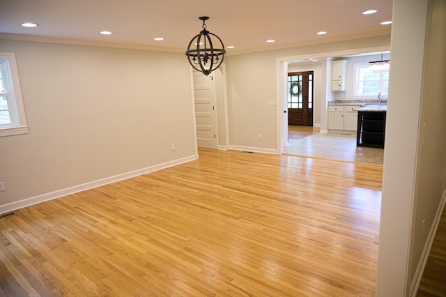 unfurnished dining area featuring baseboards, an inviting chandelier, visible vents, crown molding, and light wood-type flooring