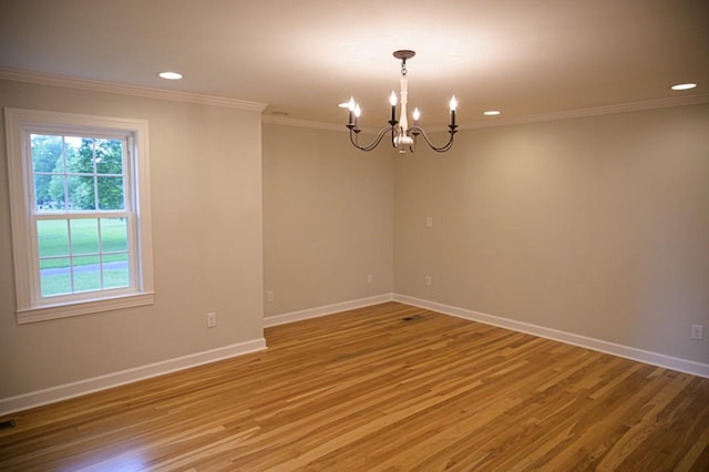 empty room with an inviting chandelier, light wood-style flooring, crown molding, and baseboards