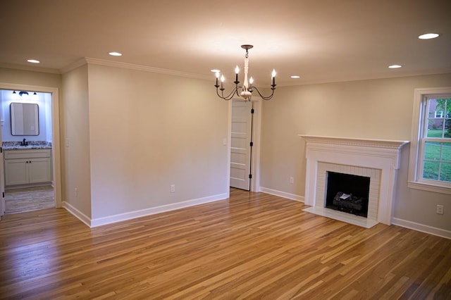 unfurnished living room featuring light wood-type flooring, recessed lighting, an inviting chandelier, and crown molding