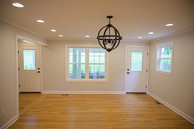 entryway with baseboards, a notable chandelier, light wood-style flooring, and crown molding