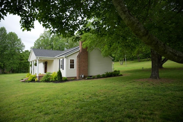 view of side of property featuring a chimney and a lawn