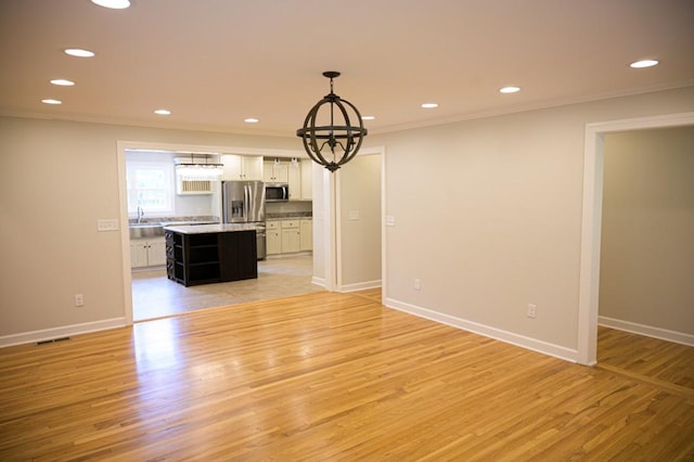 unfurnished dining area with light wood-style flooring, recessed lighting, baseboards, ornamental molding, and an inviting chandelier