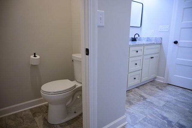 bathroom with toilet, baseboards, and vanity