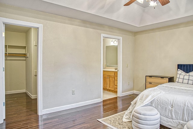 bedroom featuring a closet, baseboards, connected bathroom, a walk in closet, and wood finished floors