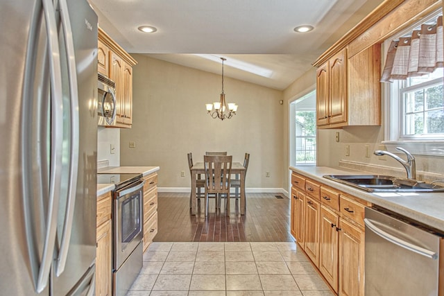 kitchen featuring lofted ceiling, a wealth of natural light, stainless steel appliances, and a sink