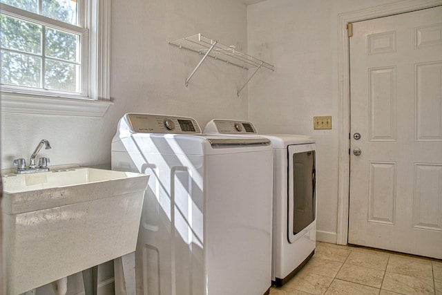 laundry room with laundry area, light tile patterned flooring, a sink, and washing machine and clothes dryer