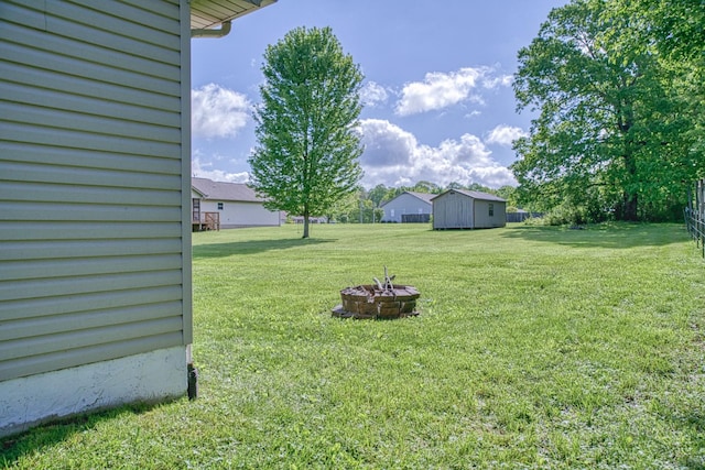 view of yard featuring a storage unit, an outdoor fire pit, and an outdoor structure